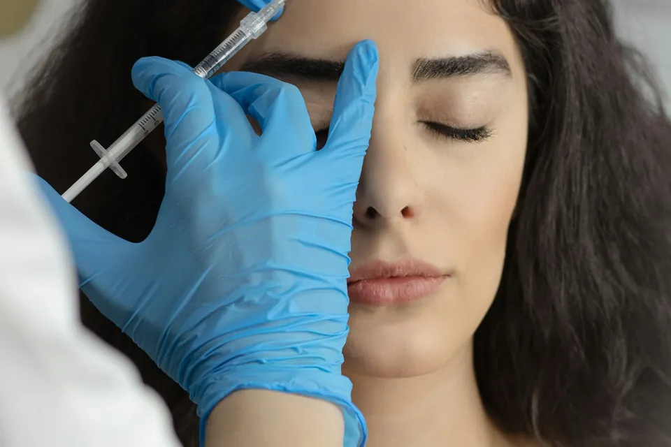 Clinician in gloves administering a precise facial injection to a relaxed patient