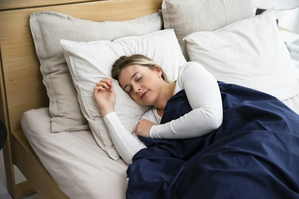 Woman sleeping soundly in bed, the aim of TMJ and sleep apnea appliance therapy