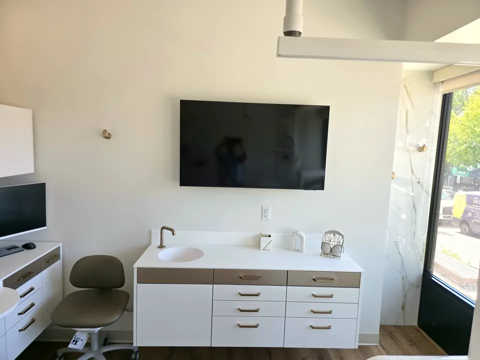 Private treatment room with a wall-mounted screen and chairside monitor